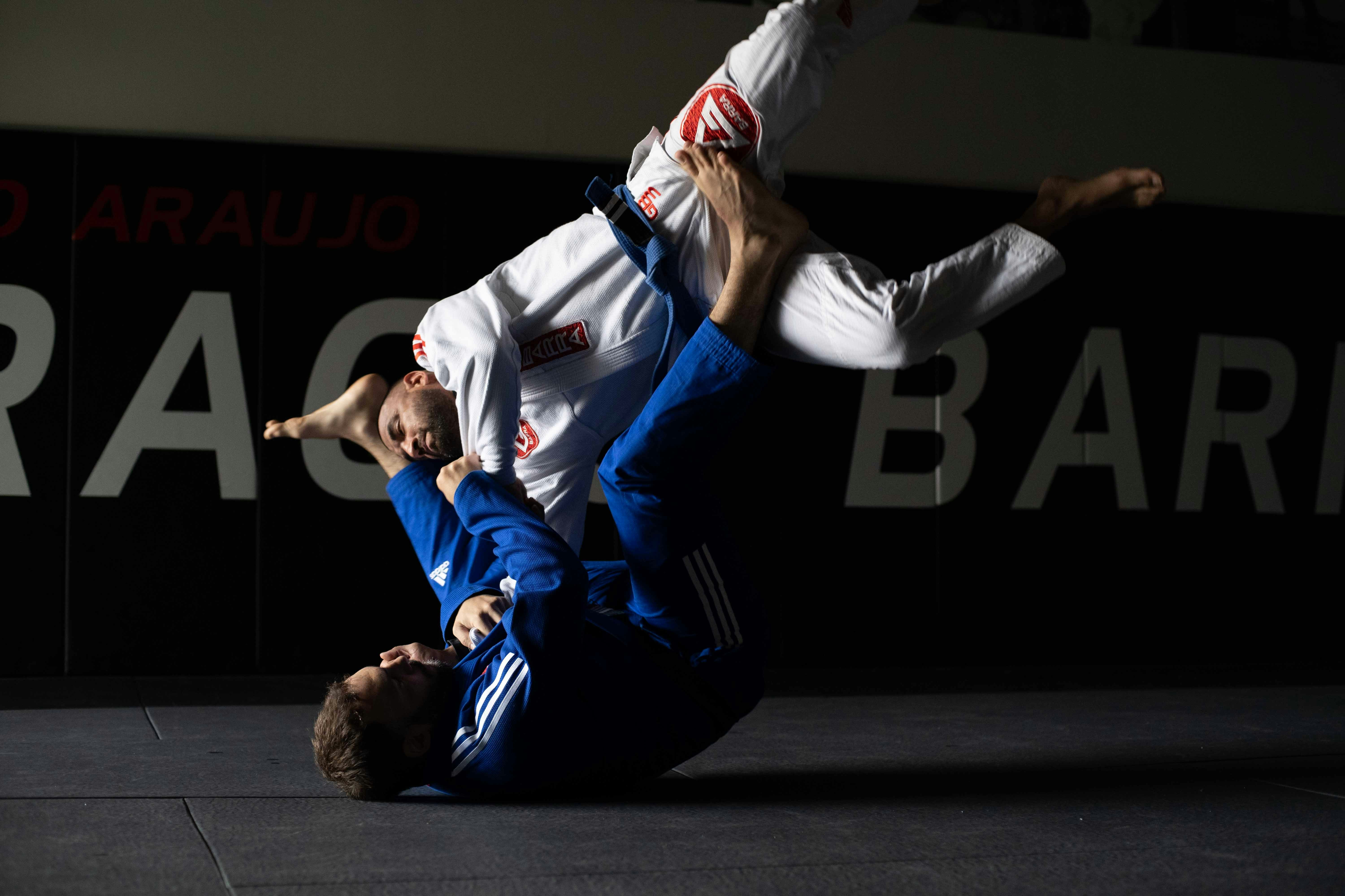 Two BJJ practitioners grappling on the mat with one athlete working a guard pass